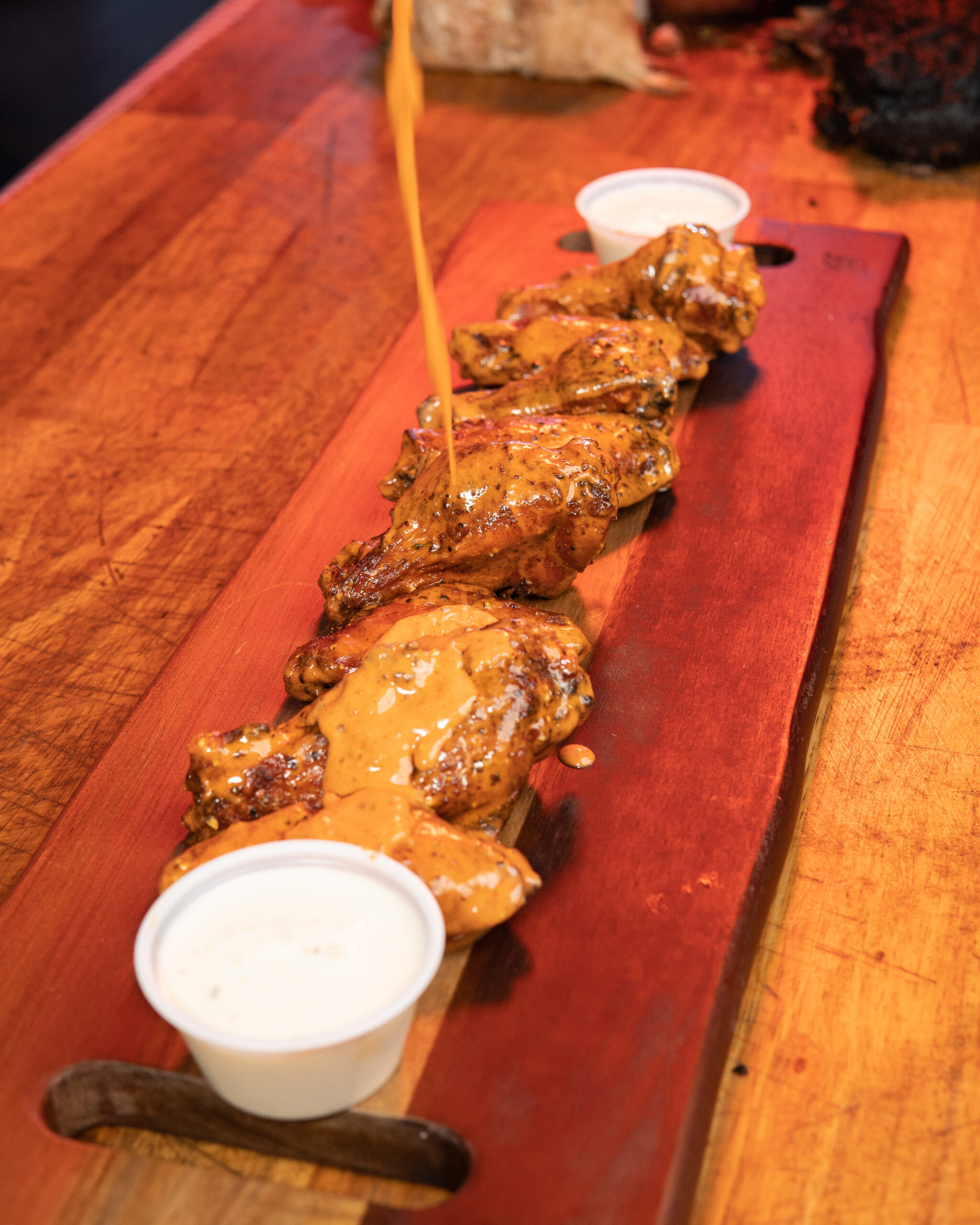 Plate of crispy chicken wings with spicy sauce and a side of celery and ranch dip, served in San Diego